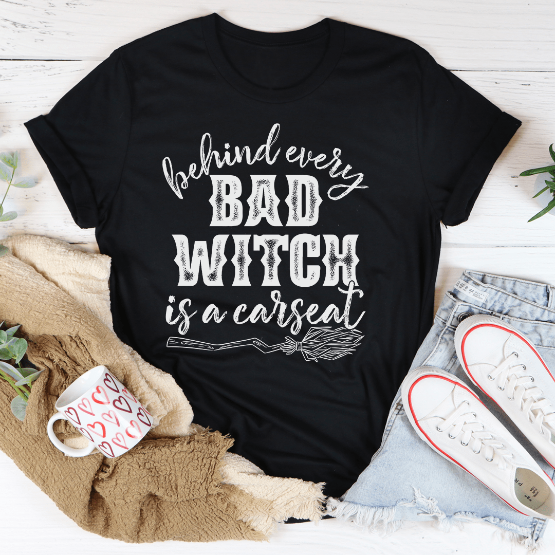 A stylish black t-shirt featuring the phrase 'Behind Every Bad Witch Is A Car Seat' printed in white, showcasing its comfortable fabric and durable stitching.