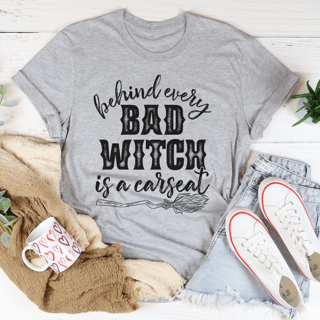 A stylish black t-shirt featuring the phrase 'Behind Every Bad Witch Is A Car Seat' printed in white, showcasing its comfortable fabric and durable stitching.