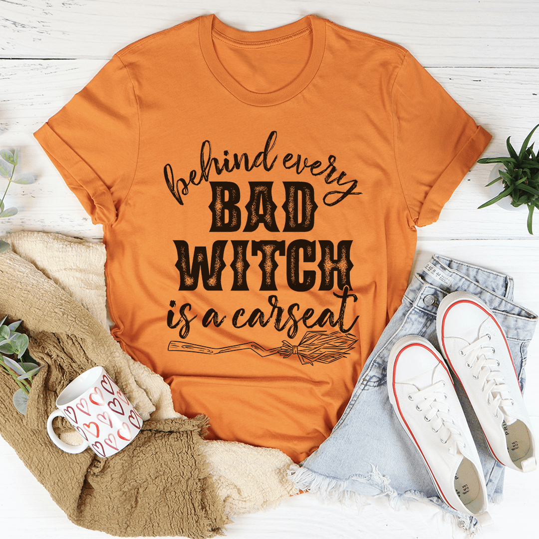 A stylish black t-shirt featuring the phrase 'Behind Every Bad Witch Is A Car Seat' printed in white, showcasing its comfortable fabric and durable stitching.