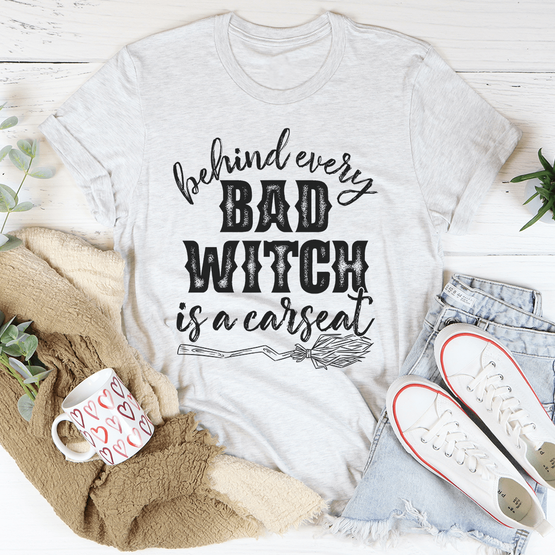 A stylish black t-shirt featuring the phrase 'Behind Every Bad Witch Is A Car Seat' printed in white, showcasing its comfortable fabric and durable stitching.