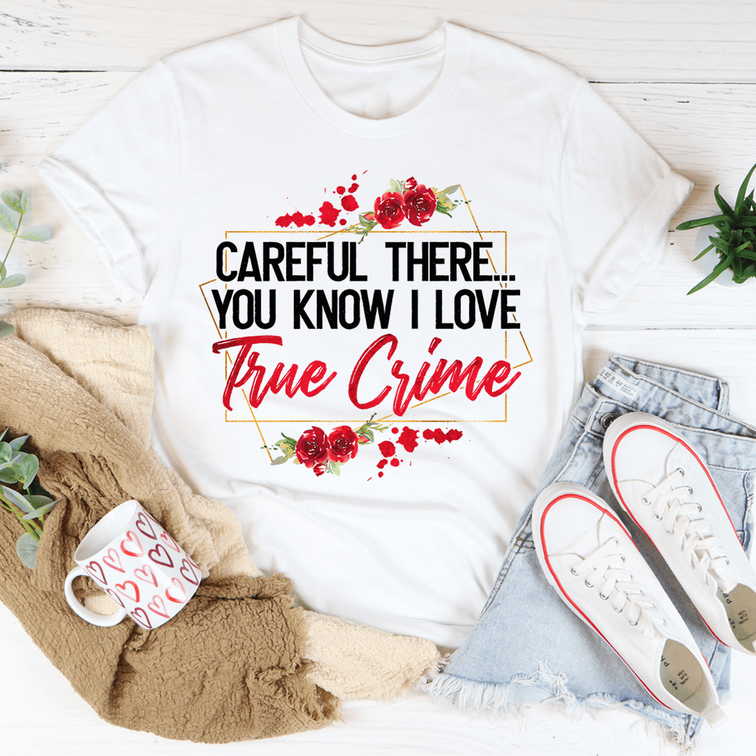 A stylish black t-shirt featuring the phrase 'Careful There You Know I Love True Crime' printed in bold letters, showcasing a love for true crime.