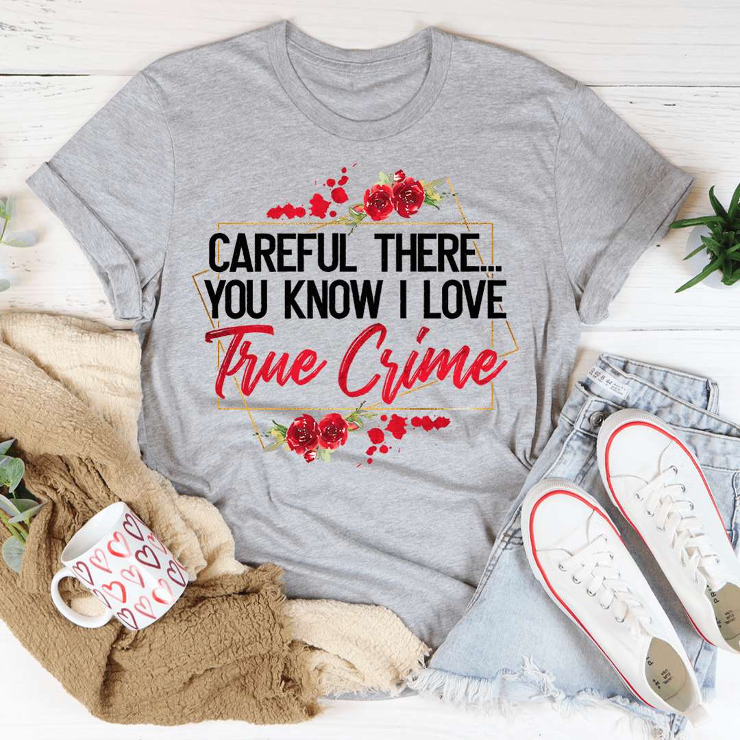 A stylish black t-shirt featuring the phrase 'Careful There You Know I Love True Crime' printed in bold letters, showcasing a love for true crime.