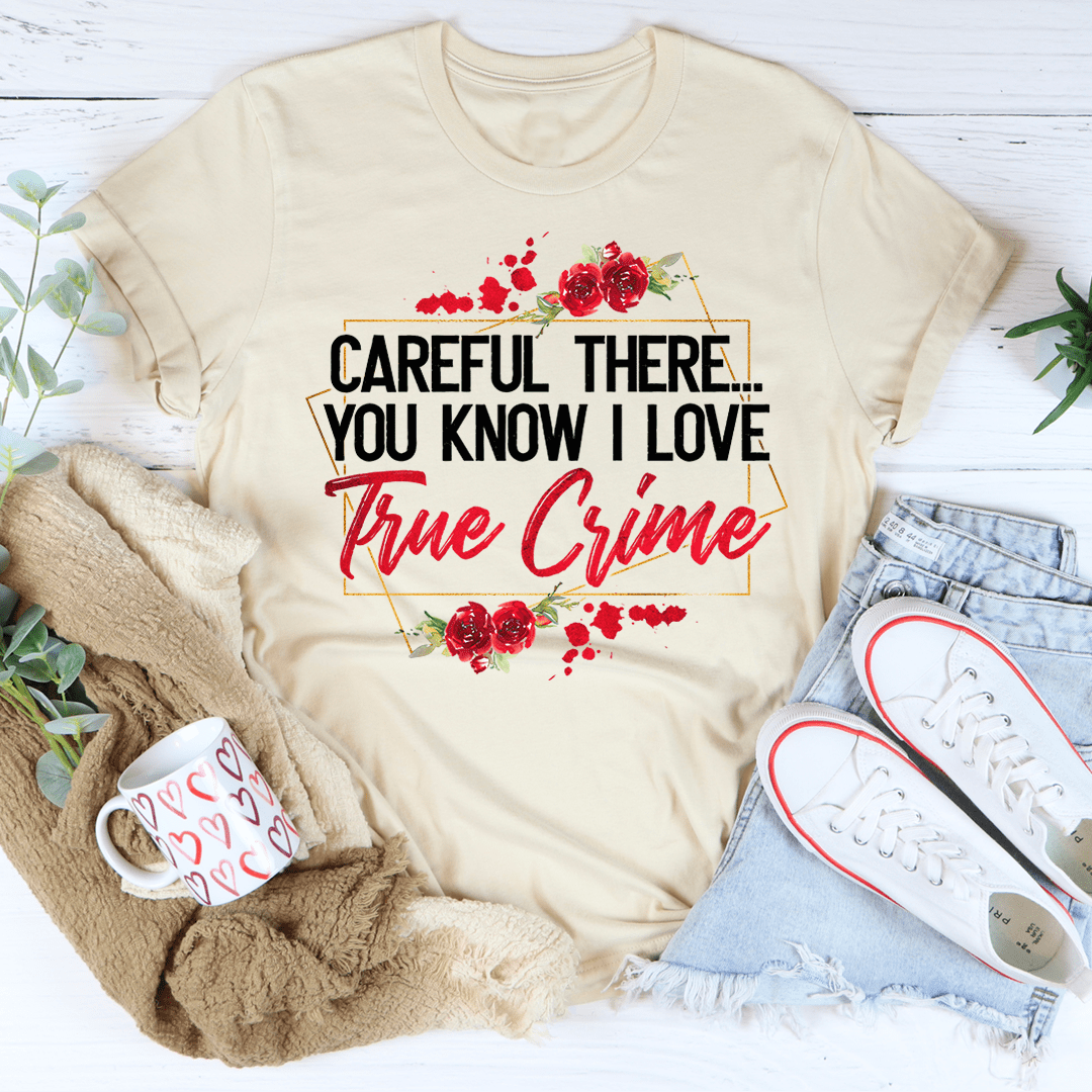 A stylish black t-shirt featuring the phrase 'Careful There You Know I Love True Crime' printed in bold letters, showcasing a love for true crime.