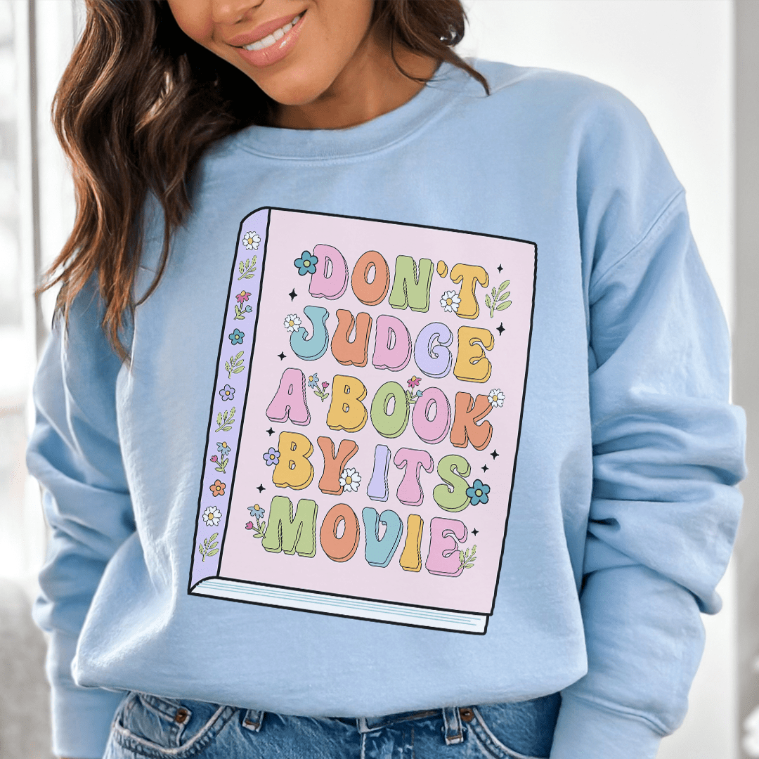 Cozy 'Don't Judge A Book' sweats featuring unique designs by top artists, made from cotton/poly fleece blend for ultimate comfort.