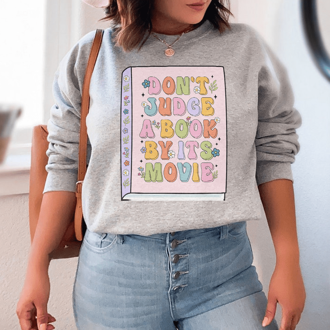 Cozy 'Don't Judge A Book' sweats featuring unique designs by top artists, made from cotton/poly fleece blend for ultimate comfort.