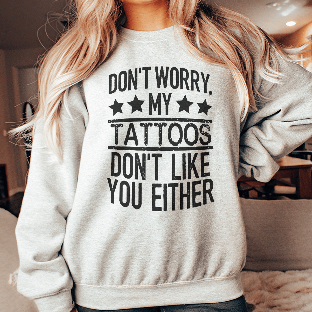 A cozy sweatshirt featuring the phrase 'Don't Worry My Tattoos Don't Like You Either', designed by top artists, showcasing a unique tattoo-inspired design.