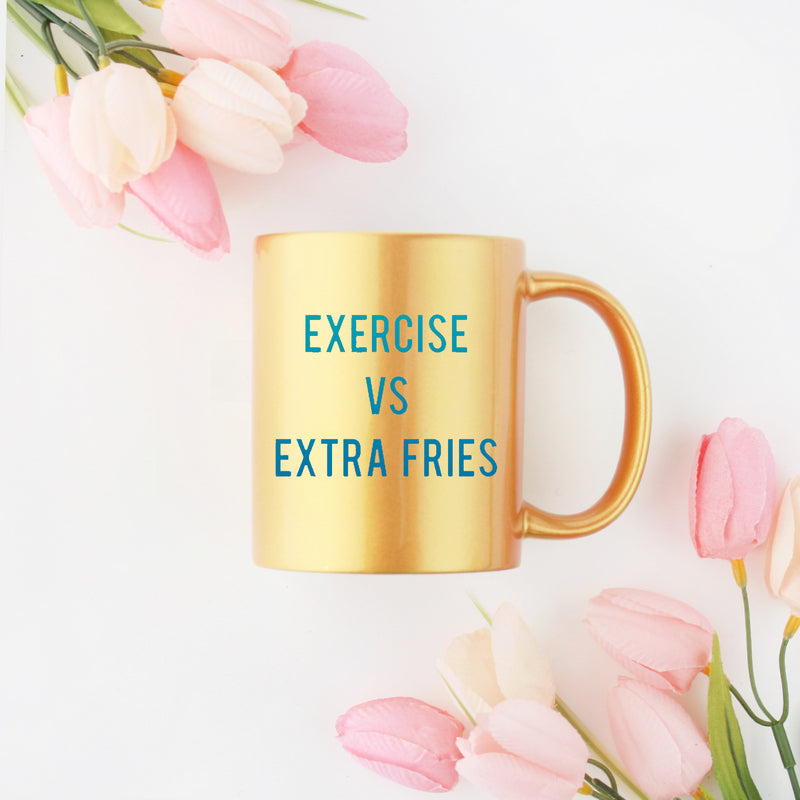 A stylish gold and silver ceramic mug with the phrase 'Exercise Versus Extra Fries' designed for fitness enthusiasts.