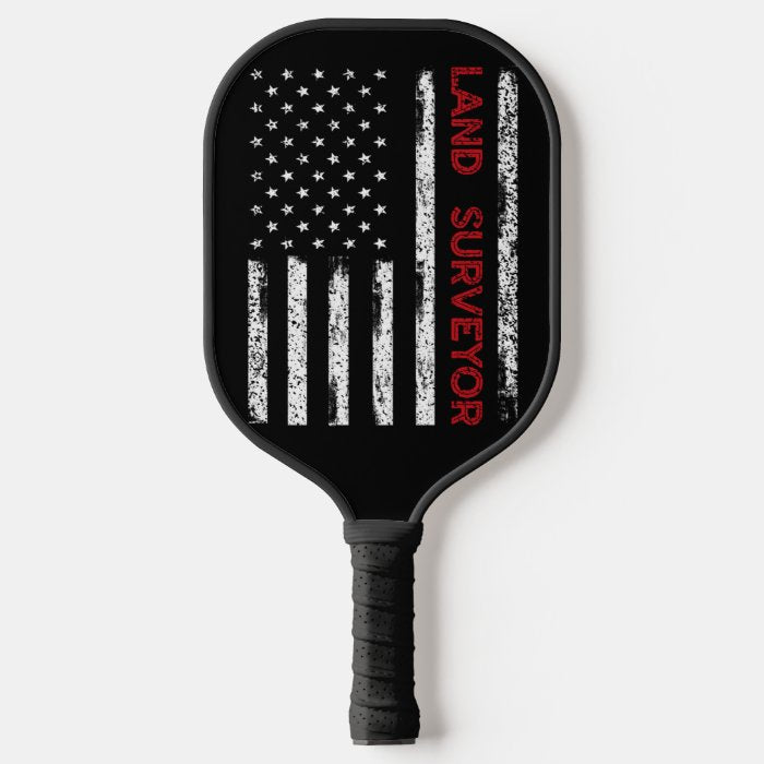 Land Sureyor Pickleball Paddle featuring a vibrant flag design, showcasing its fiberglass surface and comfortable grip.