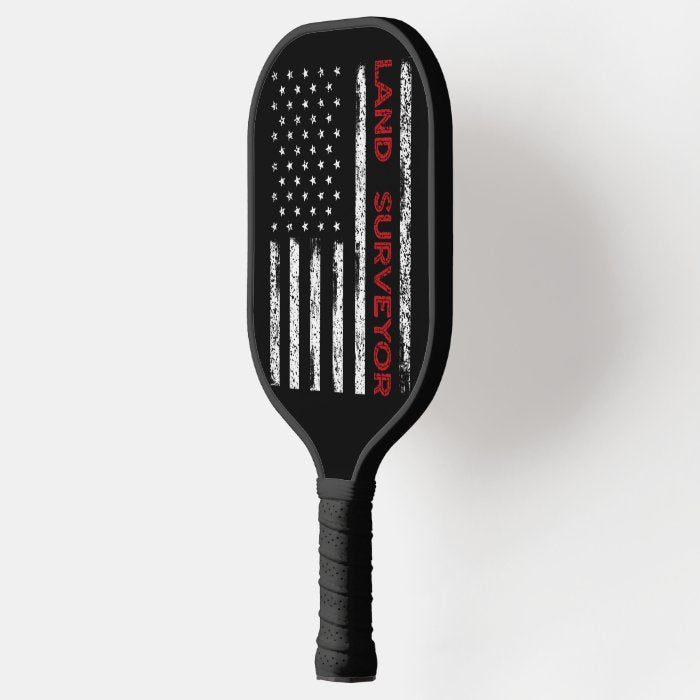 Land Sureyor Pickleball Paddle featuring a vibrant flag design, showcasing its fiberglass surface and comfortable grip.