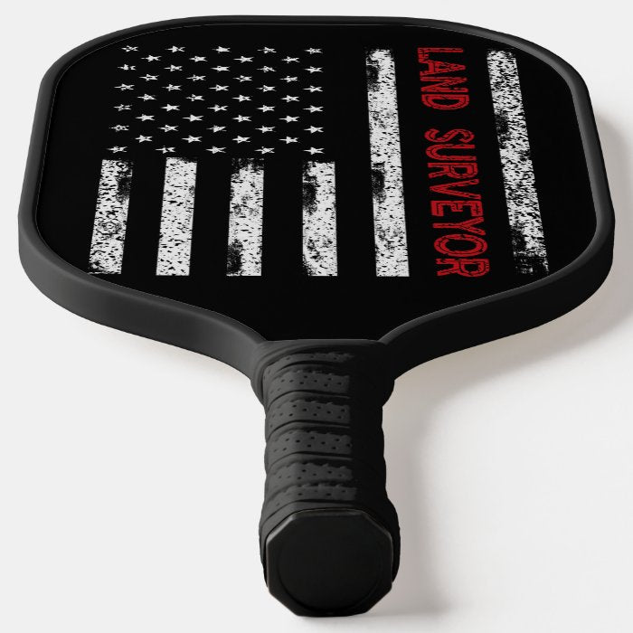 Land Sureyor Pickleball Paddle featuring a vibrant flag design, showcasing its fiberglass surface and comfortable grip.