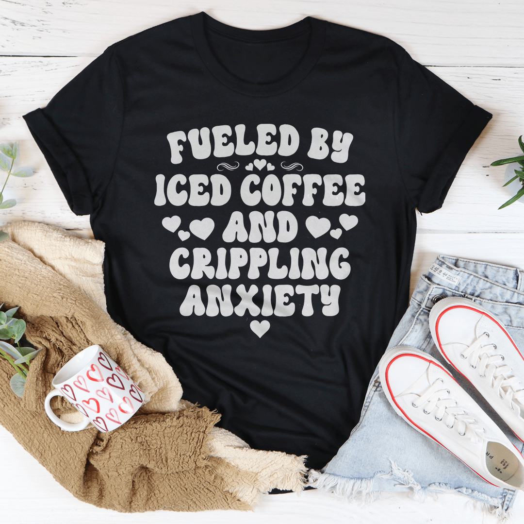 A stylish black t-shirt featuring the phrase 'Fueled By Iced Coffee And Crippling Anxiety' printed in bold, eye-catching letters.