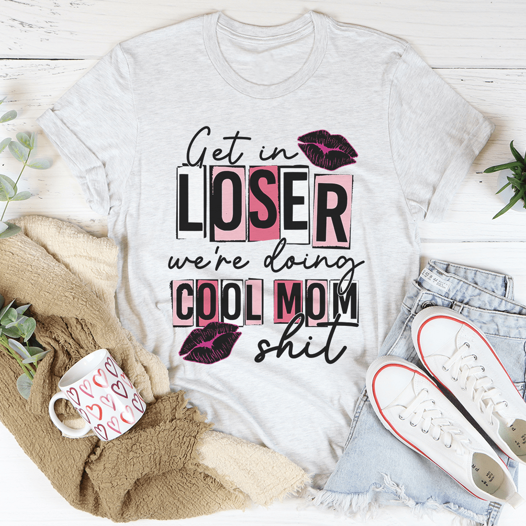 A stylish t-shirt featuring the phrase 'Get In Loser We're Doing Cool Mom Stuff' printed on soft cotton fabric, showcasing its casual and fun design.