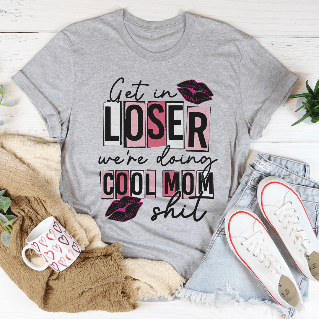 A stylish t-shirt featuring the phrase 'Get In Loser We're Doing Cool Mom Stuff' printed on soft cotton fabric, showcasing its casual and fun design.