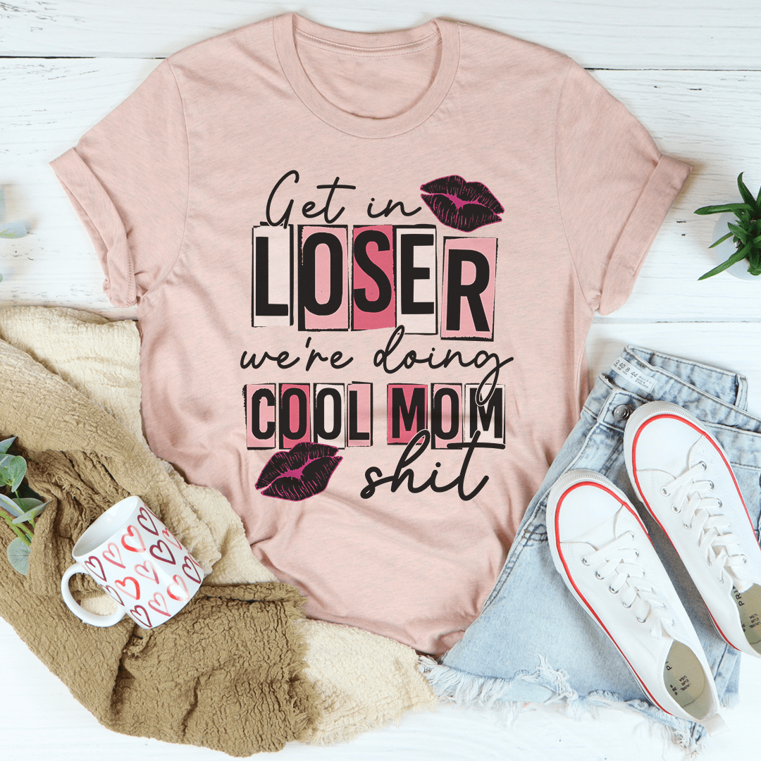 A stylish t-shirt featuring the phrase 'Get In Loser We're Doing Cool Mom Stuff' printed on soft cotton fabric, showcasing its casual and fun design.