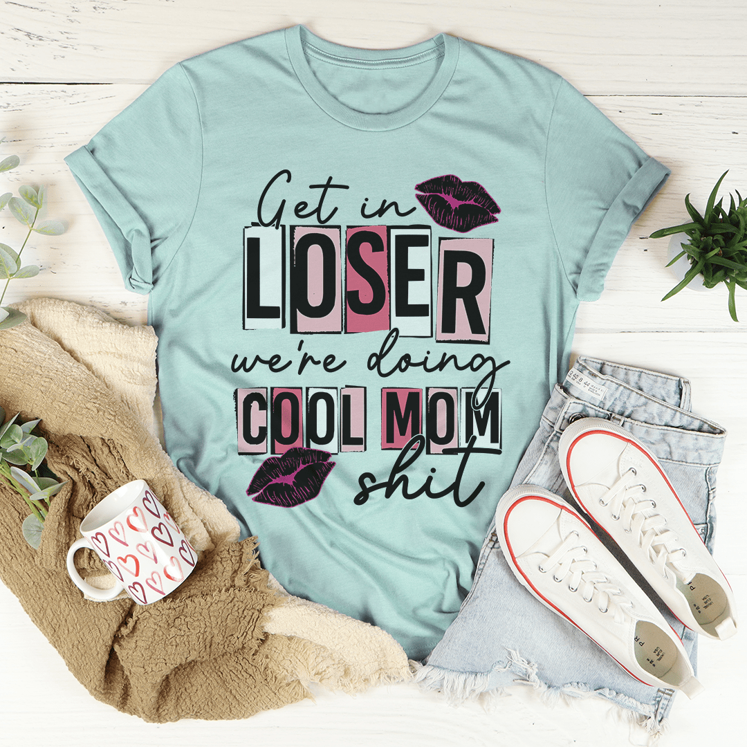 A stylish t-shirt featuring the phrase 'Get In Loser We're Doing Cool Mom Stuff' printed on soft cotton fabric, showcasing its casual and fun design.