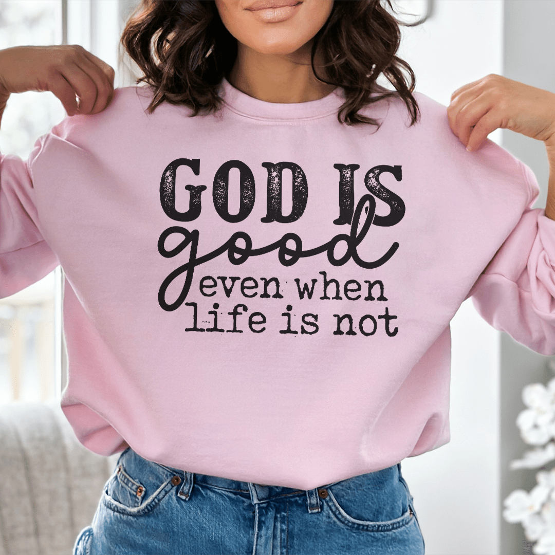 A cozy hoodie featuring the phrase 'God Is Good Even When Life Is Not', designed by top artists, showcasing a unique and stylish look.