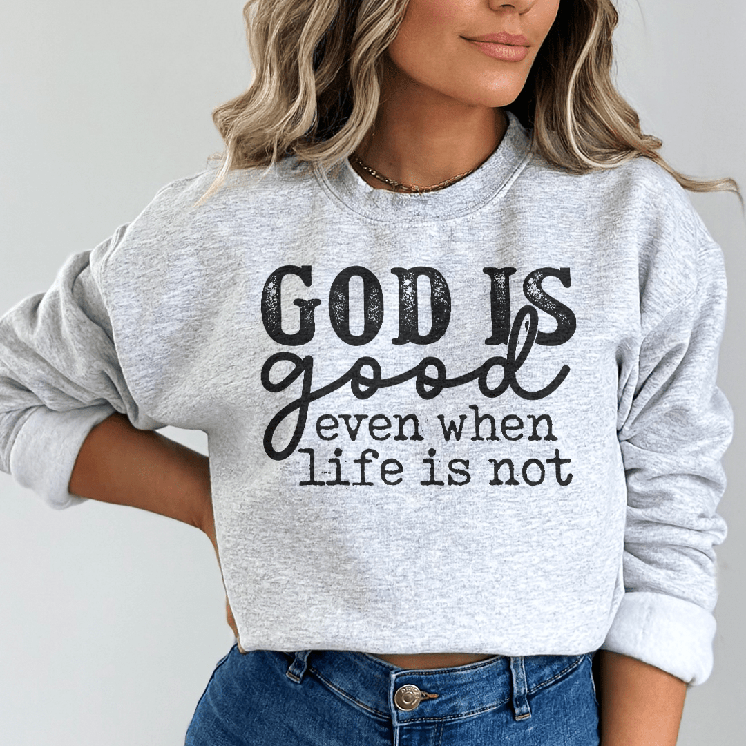 A cozy hoodie featuring the phrase 'God Is Good Even When Life Is Not', designed by top artists, showcasing a unique and stylish look.