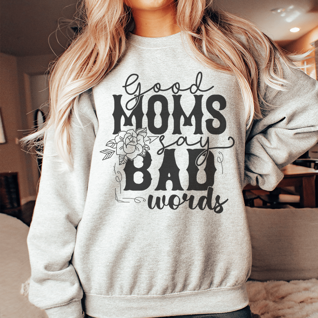 A cozy hoodie featuring the phrase 'Good Moms Say Bad Words', designed by top artists, made from a cotton/poly fleece blend.