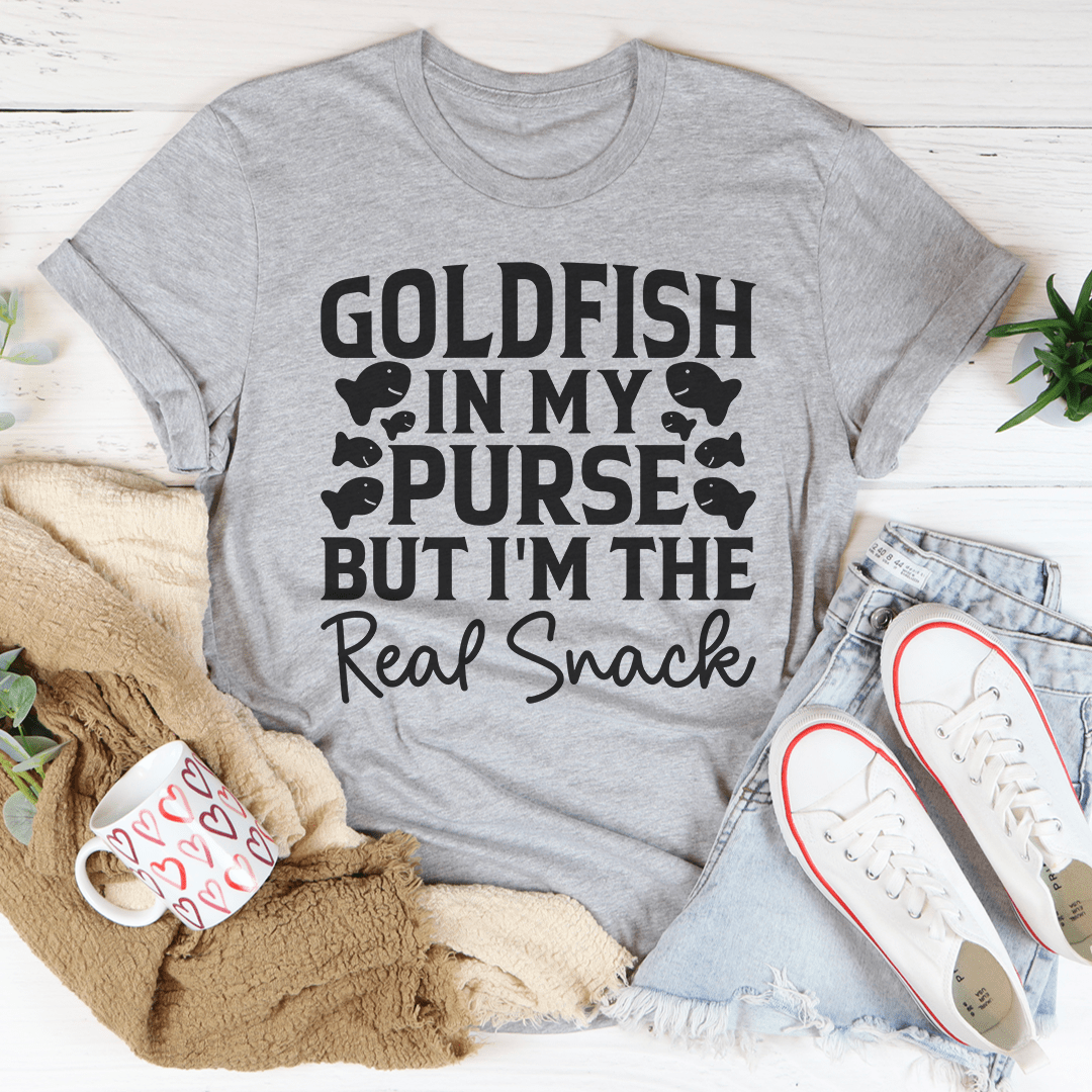 A stylish t-shirt featuring the phrase 'Goldfish In My Purse But I'm The Real Snack' in a playful design, made from soft cotton.