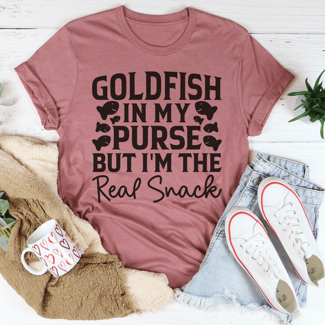 A stylish t-shirt featuring the phrase 'Goldfish In My Purse But I'm The Real Snack' in a playful design, made from soft cotton.