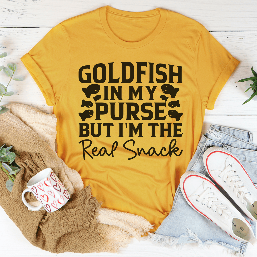 A stylish t-shirt featuring the phrase 'Goldfish In My Purse But I'm The Real Snack' in a playful design, made from soft cotton.