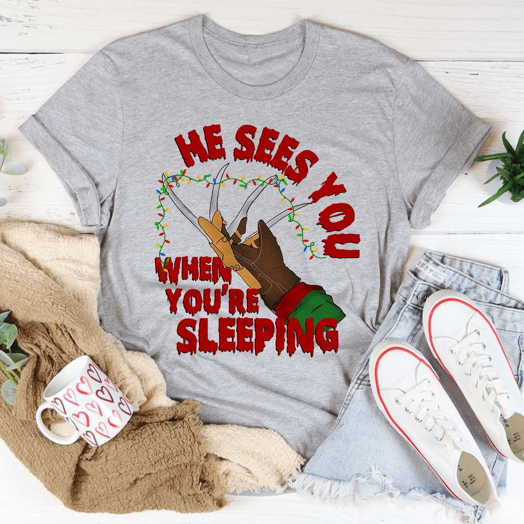 He Sees You When You're Sleeping T-Shirt featuring a whimsical design, made from soft ring-spun cotton with double stitching for durability.