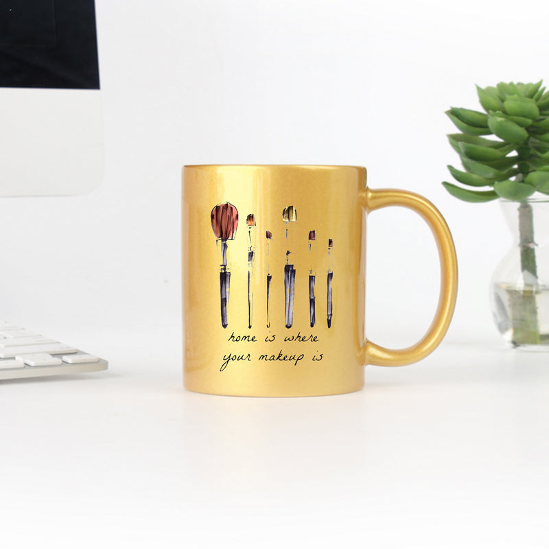 Elegant gold and silver ceramic mug with makeup-themed design, perfect for stylish drinkware.