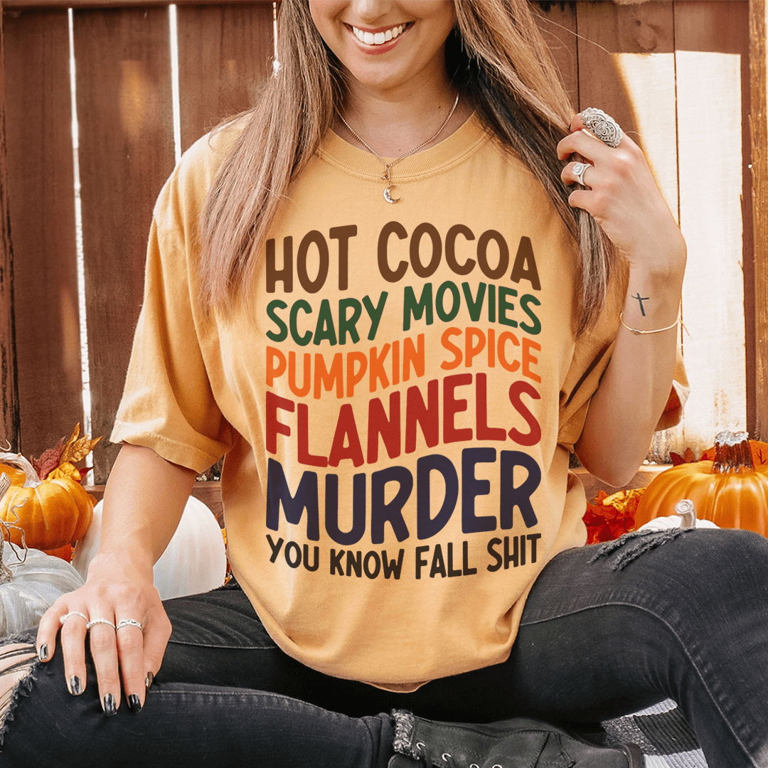 A cozy t-shirt featuring a fun design with hot cocoa, scary movies, and pumpkin spice themes, perfect for fall.