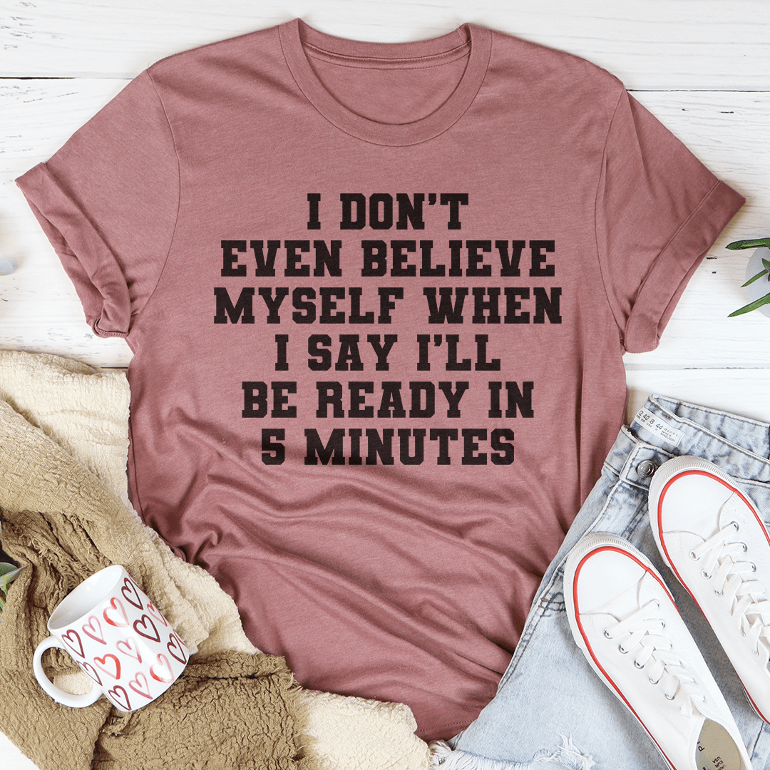 A humorous t-shirt featuring the phrase 'I Don’t Even Believe Myself When I Say I’ll Be Ready In 5 Minutes', made of soft cotton.