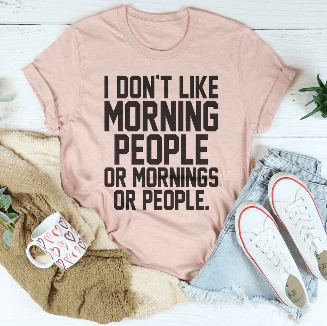 A black t-shirt with the phrase 'I Don't Like Morning People Or Mornings Or People' printed in bold white letters, showcasing a casual and humorous design.