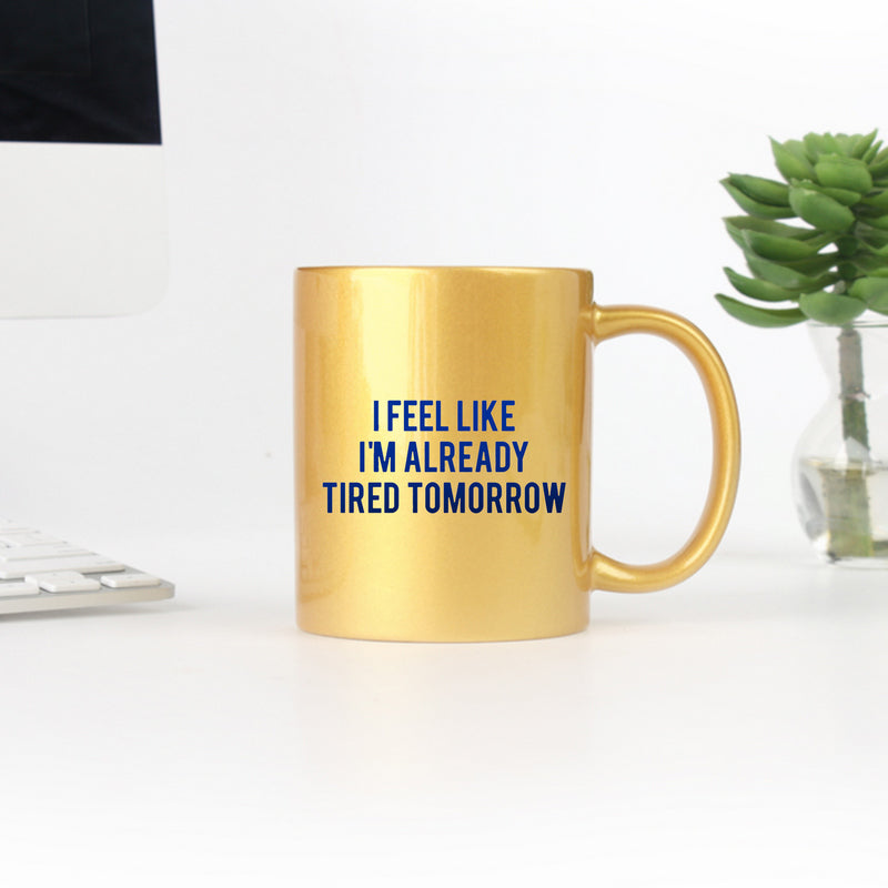 Ceramic mug with gold metallic coating featuring the phrase 'I Feel Like I'm Already Tired Tomorrow' in a stylish design.