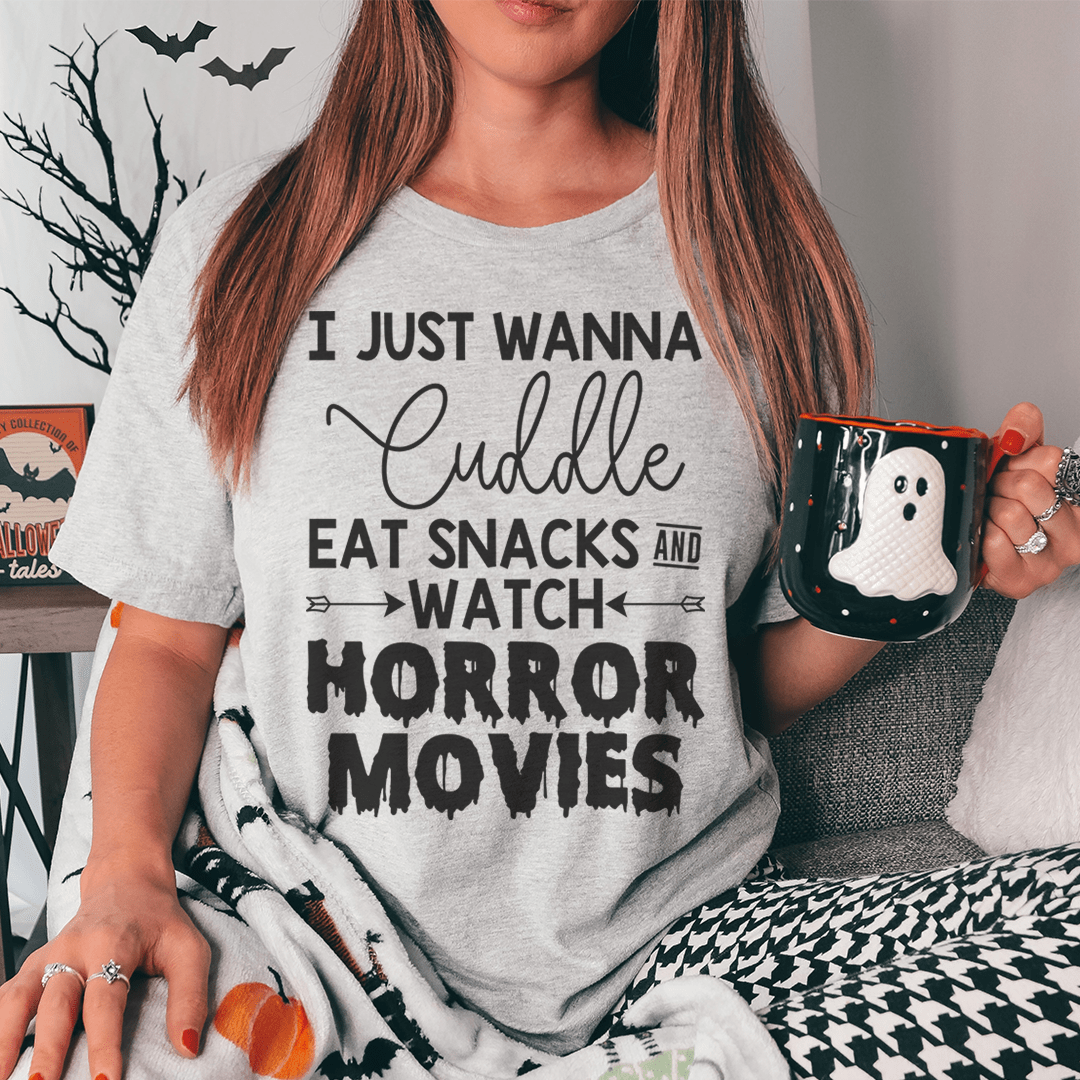 A cozy t-shirt featuring the slogan 'I Just Wanna Cuddle Eat Snacks Watch Horror Movies', made from soft cotton with double stitching.