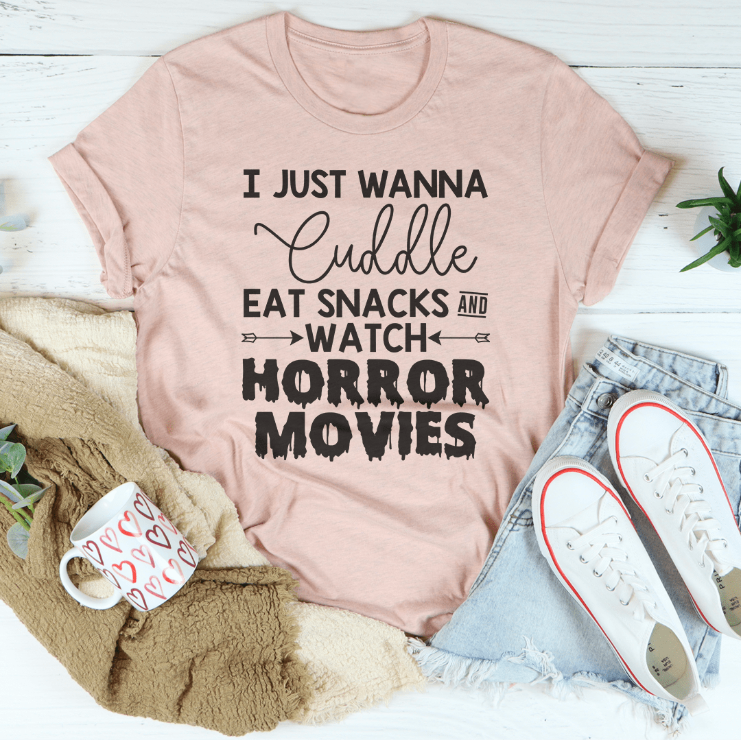 A cozy t-shirt featuring the slogan 'I Just Wanna Cuddle Eat Snacks Watch Horror Movies', made from soft cotton with double stitching.