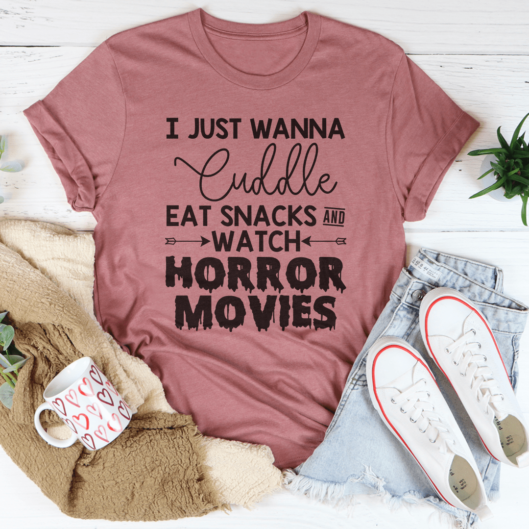 A cozy t-shirt featuring the slogan 'I Just Wanna Cuddle Eat Snacks Watch Horror Movies', made from soft cotton with double stitching.