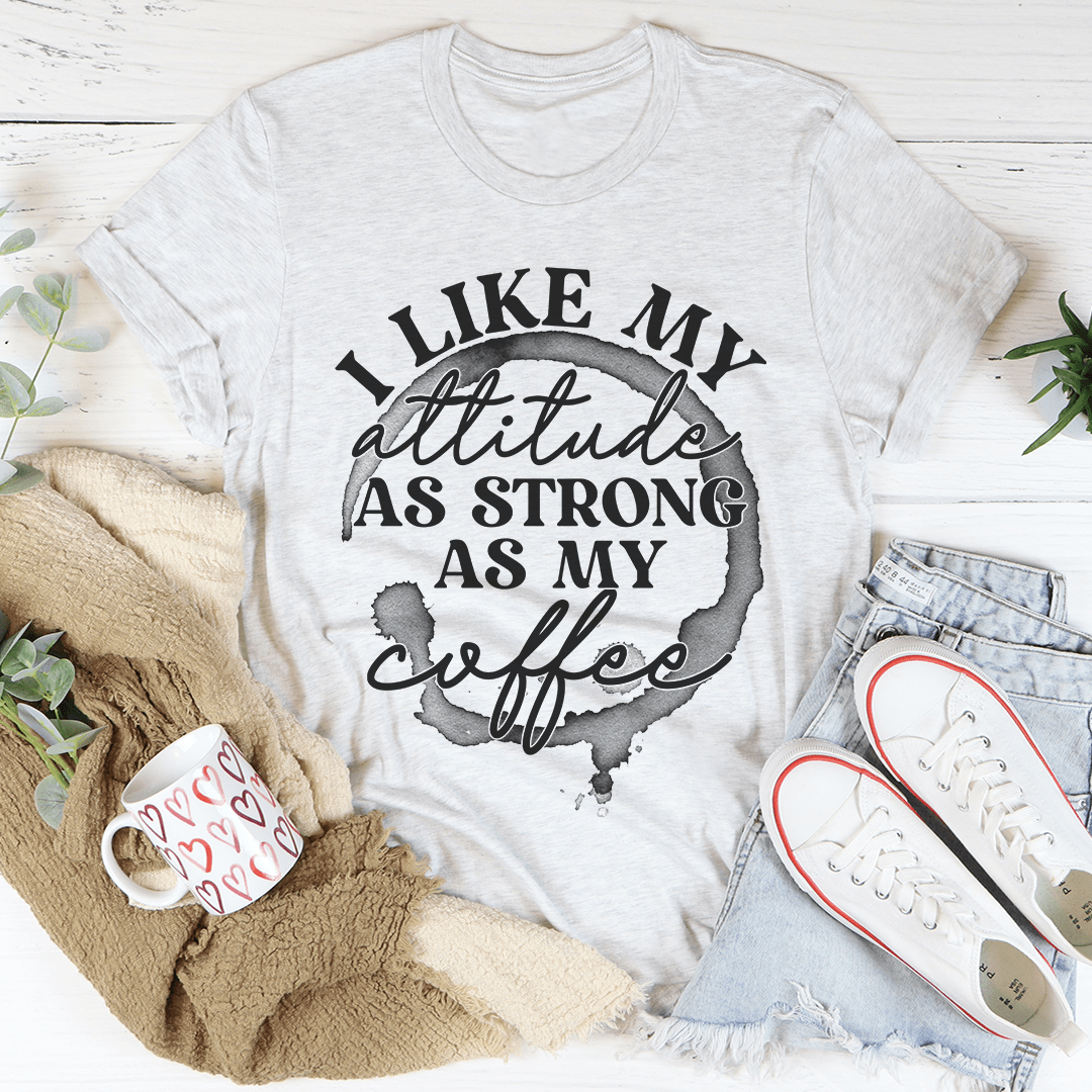 A stylish black t-shirt with the phrase 'I Like My Attitude As Strong As My Coffee' printed in bold white letters, showcasing its soft fabric and durable stitching.