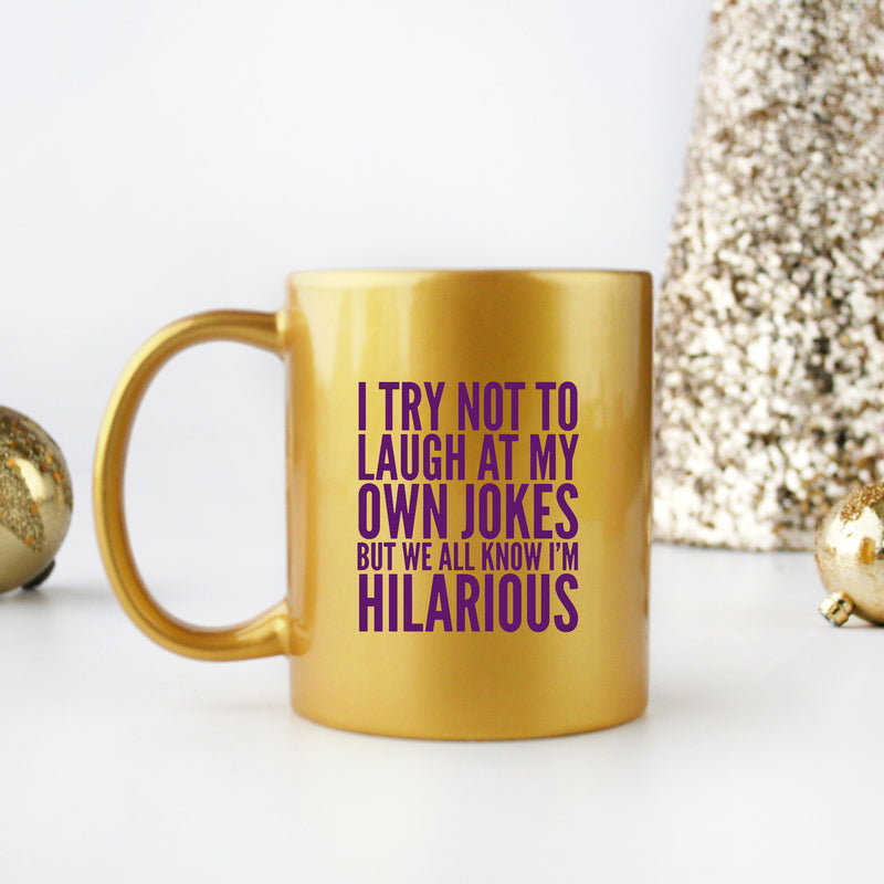 Ceramic mug with gold and silver design featuring the phrase 'I Try Not To Laugh At My Own Jokes'.