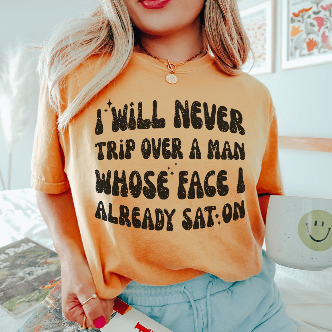 A humorous t-shirt featuring the phrase 'I Will Never Trip Over A Man Whose Face I Already Sat On', made from soft cotton.