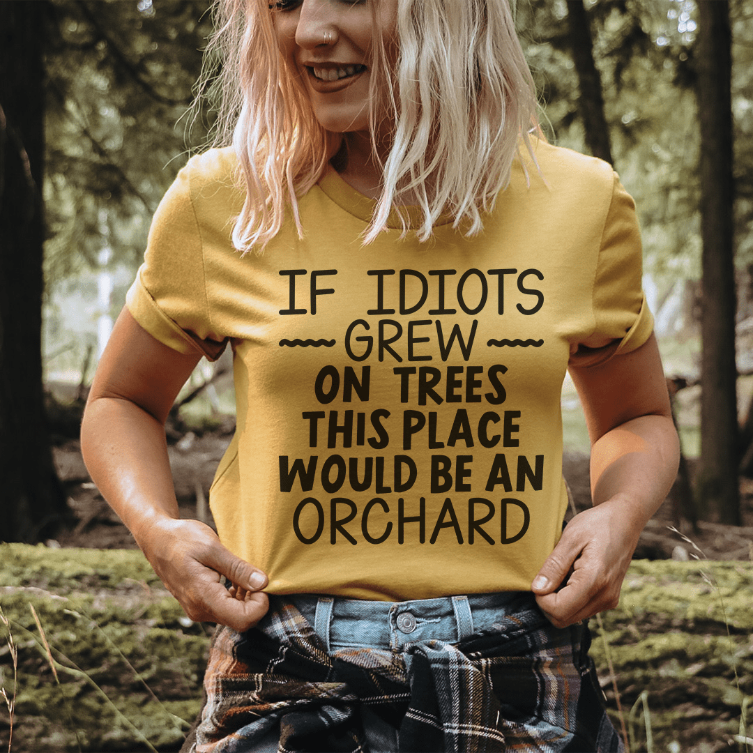 A humorous t-shirt featuring the phrase 'If Idiots Grew On Trees This Place Would Be An Orchard' printed on soft cotton fabric.