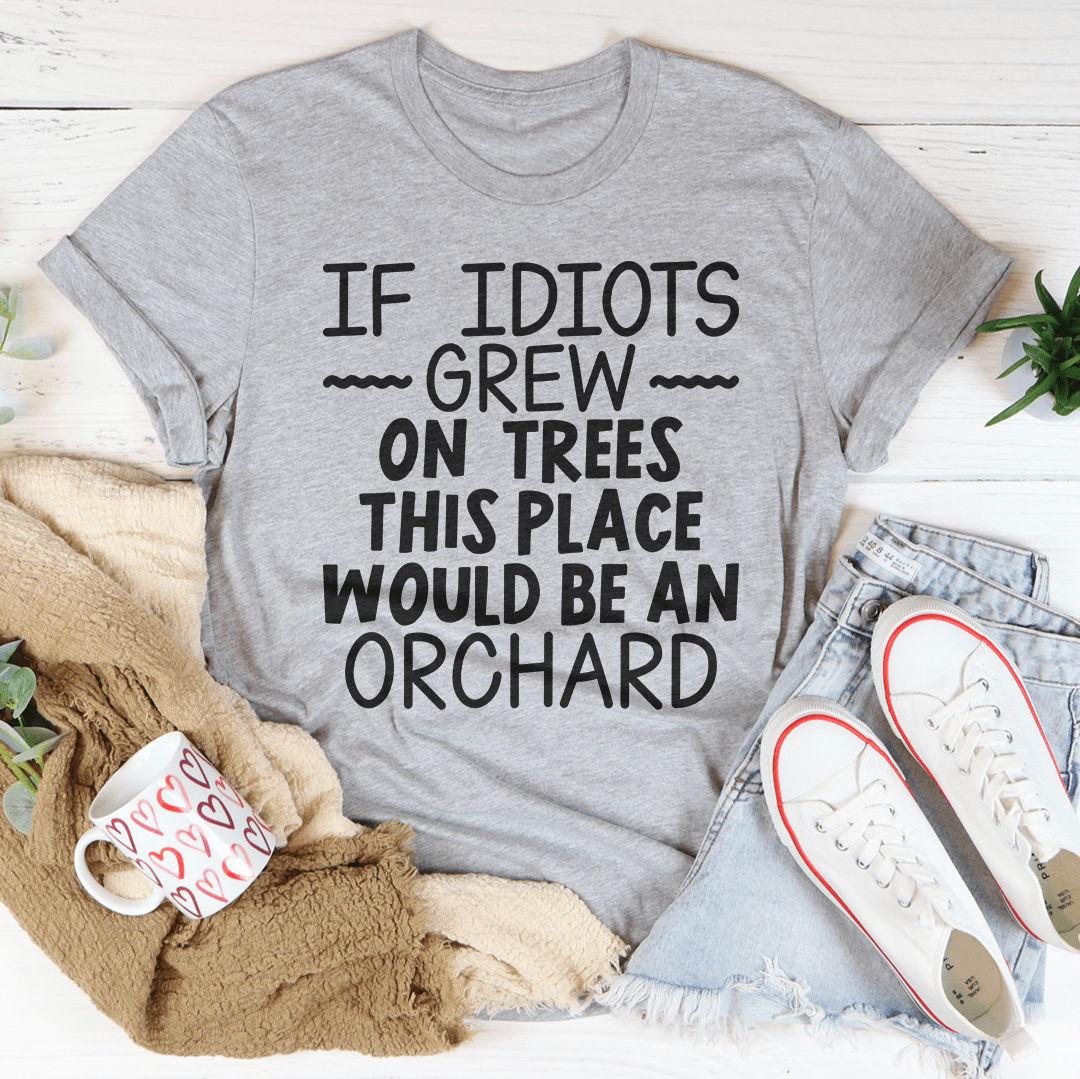 A humorous t-shirt featuring the phrase 'If Idiots Grew On Trees This Place Would Be An Orchard' printed on soft cotton fabric.