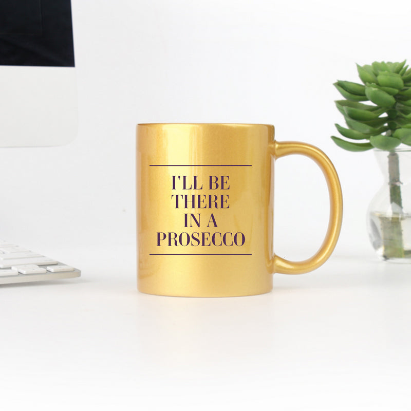 A stylish gold and silver ceramic mug with the phrase 'I'll Be There In A Prosecco' elegantly displayed.