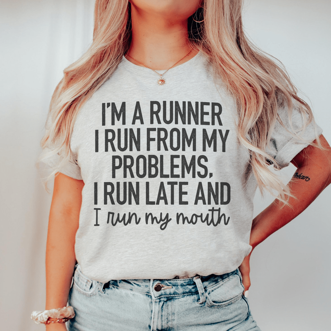 A humorous t-shirt featuring the phrase 'I'm A Runner I Run From My Problems, I Run Late And I Run My Mouth' in bold print, made from soft cotton.