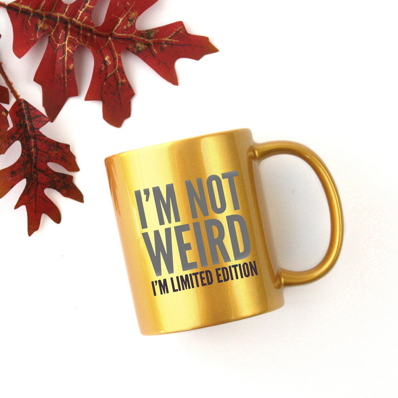 Ceramic gold and silver mug with the phrase 'I'm Not Weird, I'm Limited Edition' printed on it, showcasing a unique design.