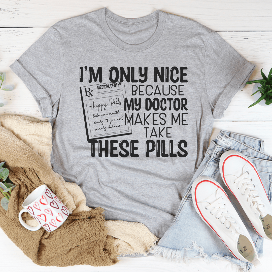 A humorous t-shirt featuring the phrase 'I'm Only Nice Because My Doctor Makes Me Take These Pills', made from soft cotton with double stitching.