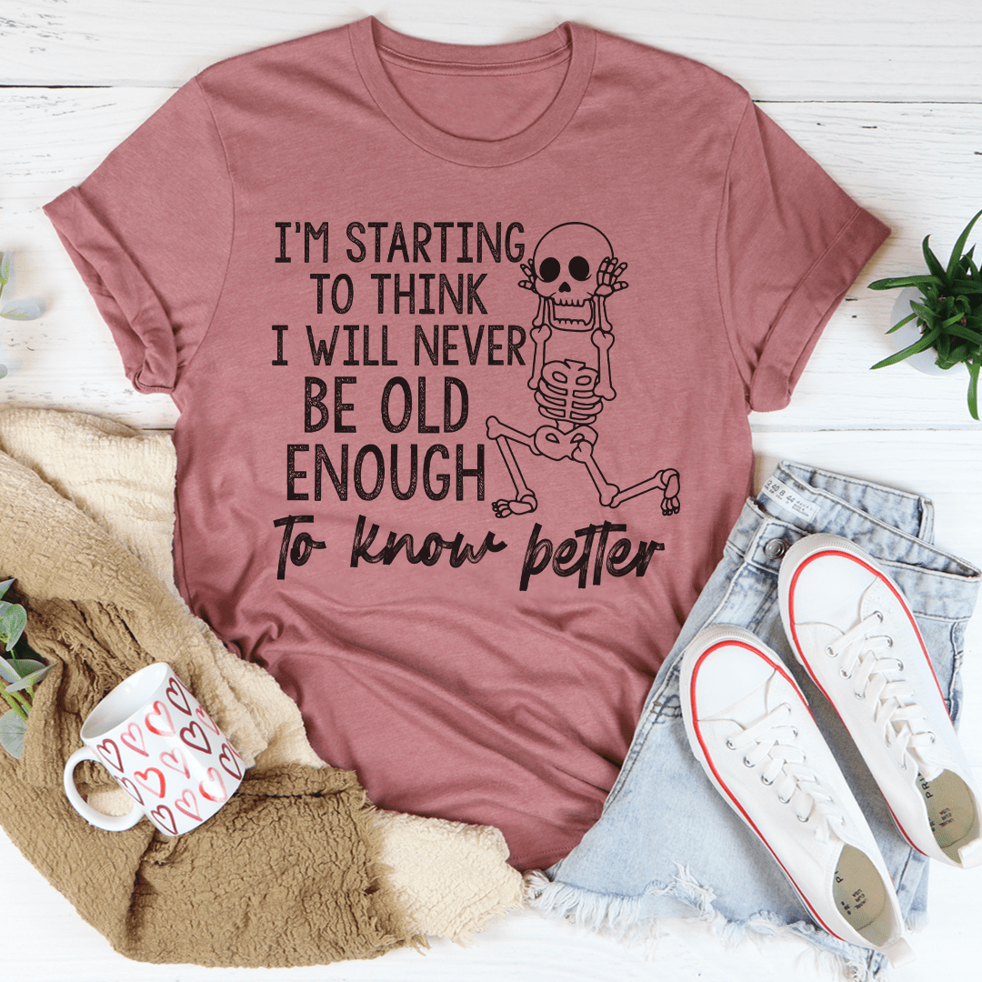 A stylish t-shirt featuring the phrase 'I'm Starting To Think I Will Never Be Old Enough To Know Better', made from soft cotton with durable stitching.