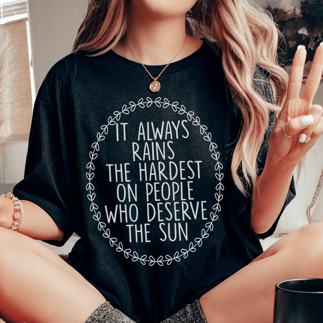 A soft, durable t-shirt featuring the phrase 'It Always Rains The Hardest On People Who Deserve The Sun' printed in vibrant colors.