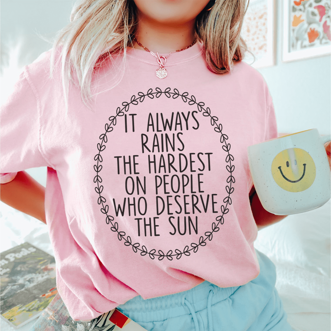 A soft, durable t-shirt featuring the phrase 'It Always Rains The Hardest On People Who Deserve The Sun' printed in vibrant colors.