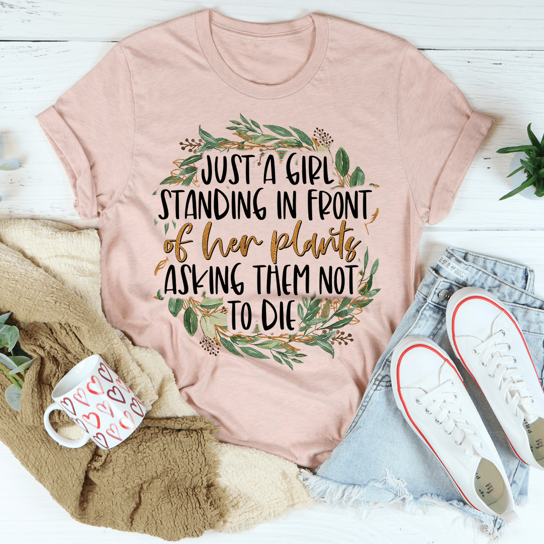 A stylish t-shirt featuring the phrase 'Just A Girl Standing In Front Of Her Plants', made from soft cotton with double stitching.