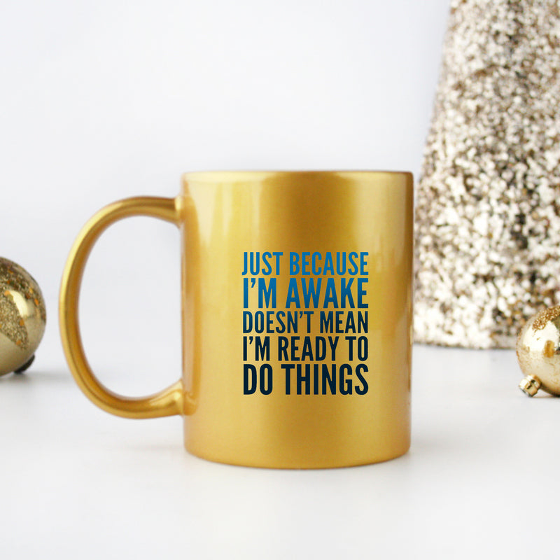 Ceramic mug with gold metallic coating featuring the phrase 'Just Because I'm Awake Doesn't Mean I'm Ready To Do Things' in stylish typography.