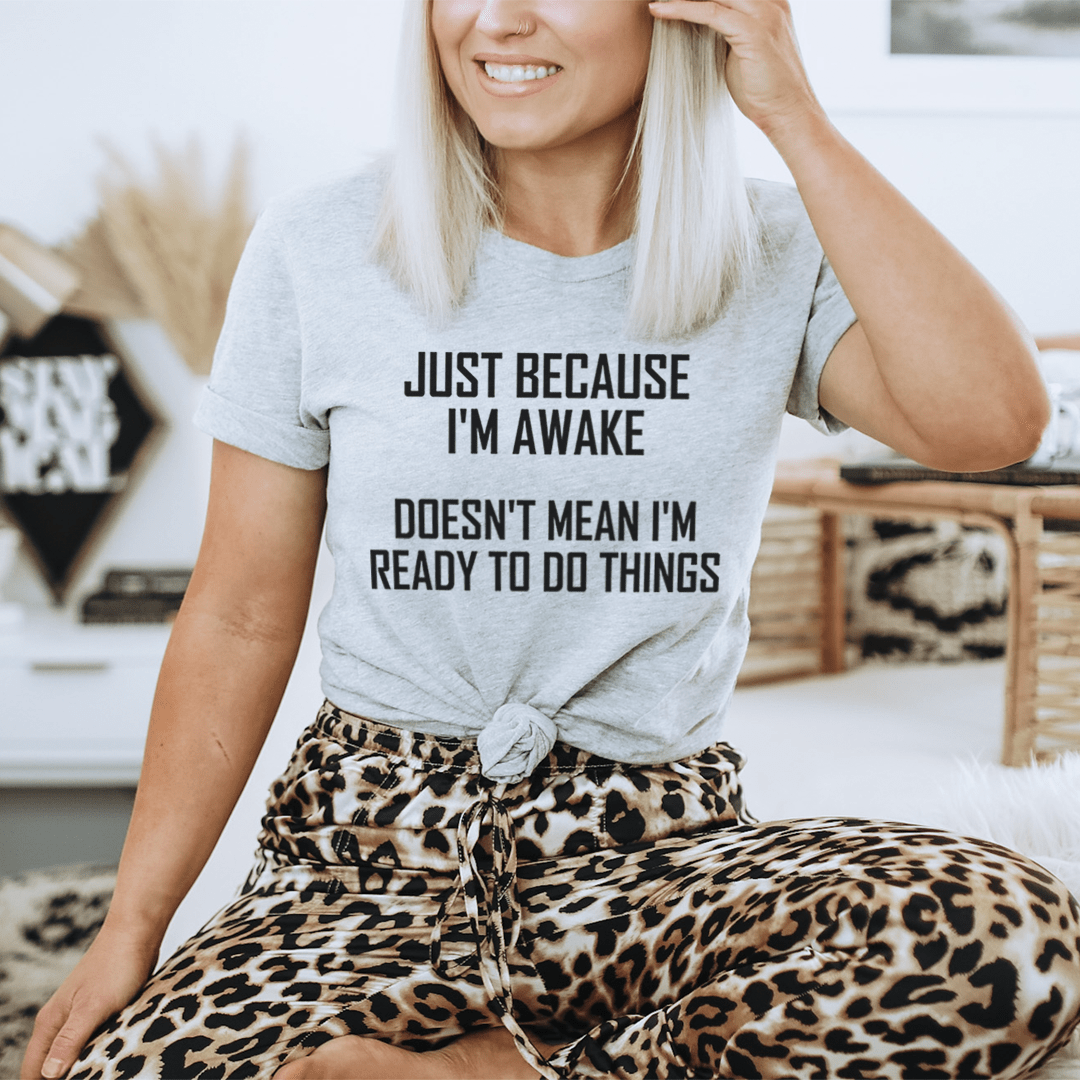 A comfortable and stylish t-shirt featuring the phrase 'Just Because I'm Awake Doesn't Mean I'm Ready To Do Things', made from soft ring-spun cotton.