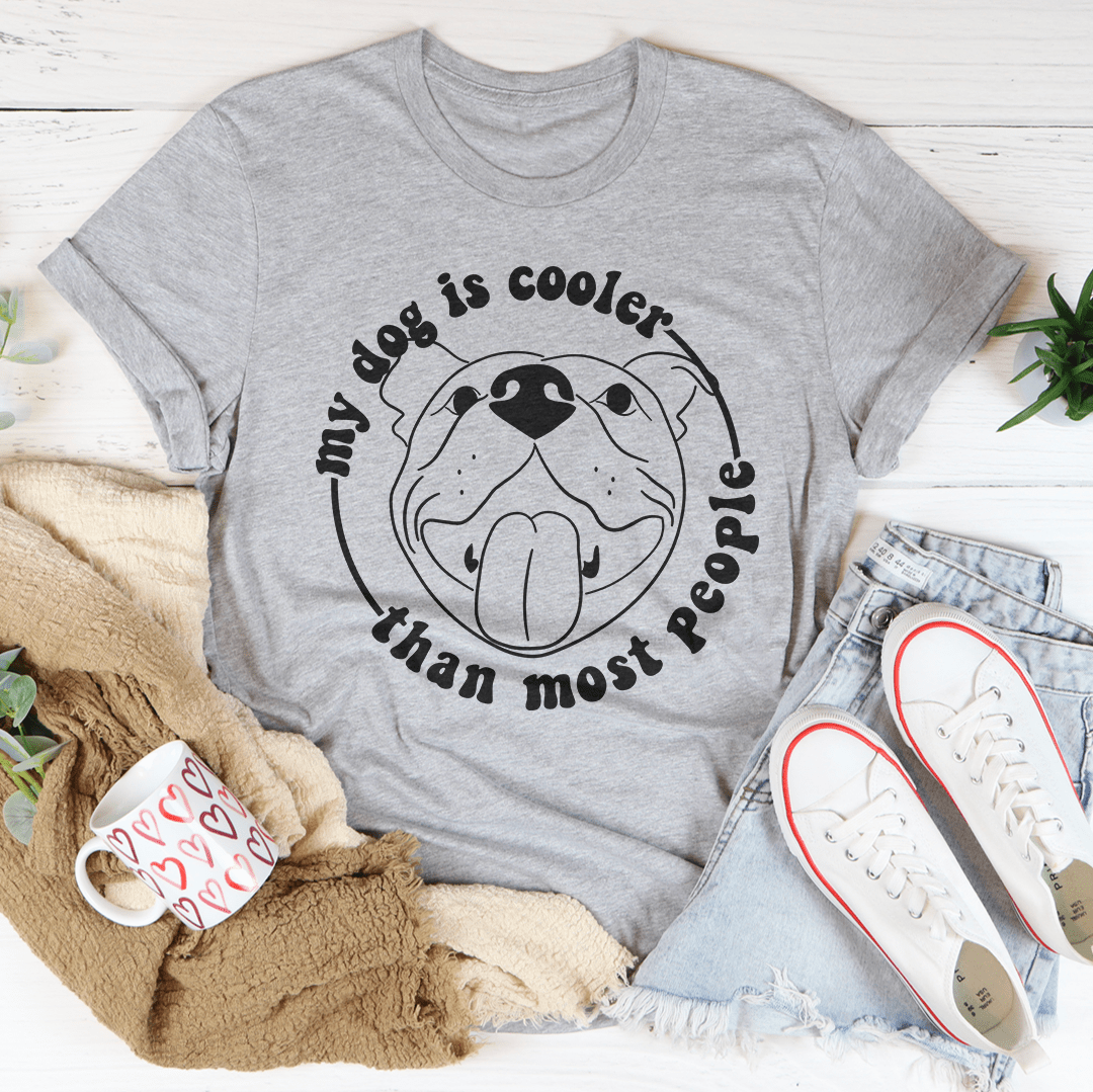 A stylish t-shirt featuring the phrase 'My Dog Is Cooler Than Most People' printed on it, made from soft cotton fabric.